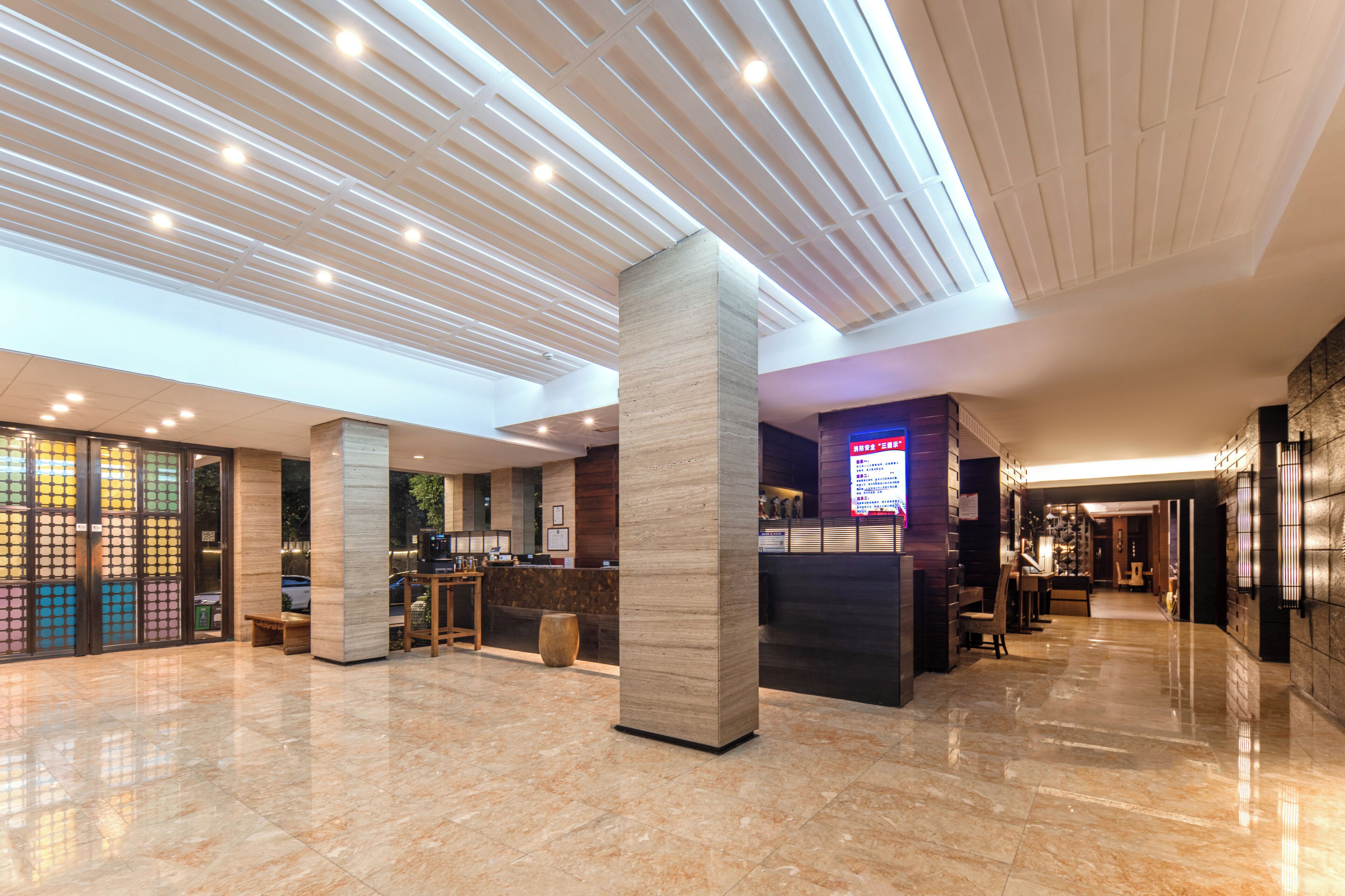A spacious lobby with a high ceiling, large pillars, a reception desk, and a glass storefront.
