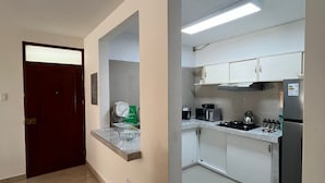 A modern kitchen with white cabinets, a stainless steel refrigerator, and a built-in oven. - 🏡 Cozy Apartment in Piura - Safe, Central and Comfortable (Piura)