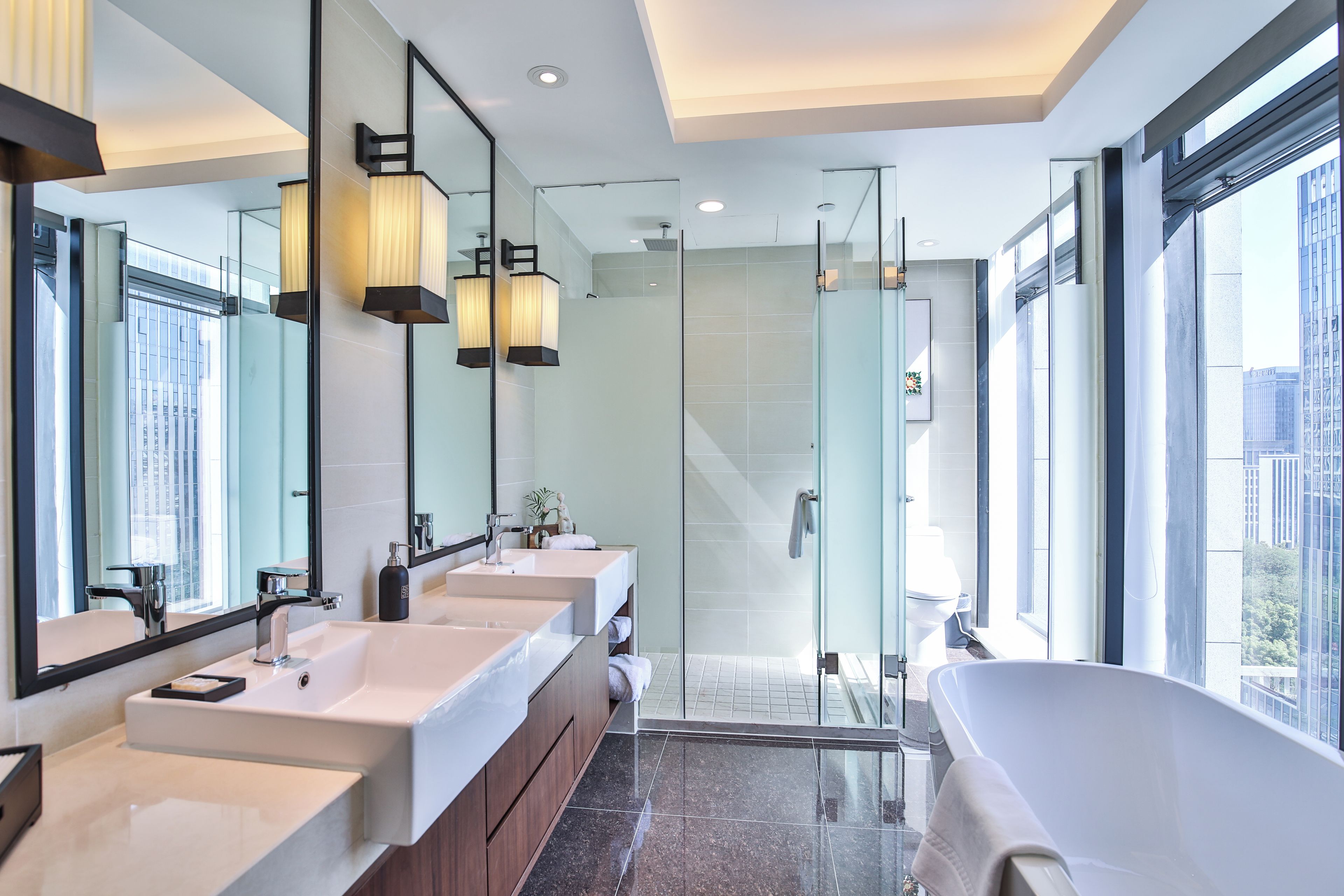 A modern bathroom with three sinks, a large mirror, and a walk-in shower.