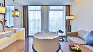 A modern bathroom with a large bathtub, a vanity with a mirror, and a sofa with a fruit bowl. - SSAW Boutique Hotel Hangzhou Qianjiang New City Jinjiang Subway Station Branch (Hangzhou)
