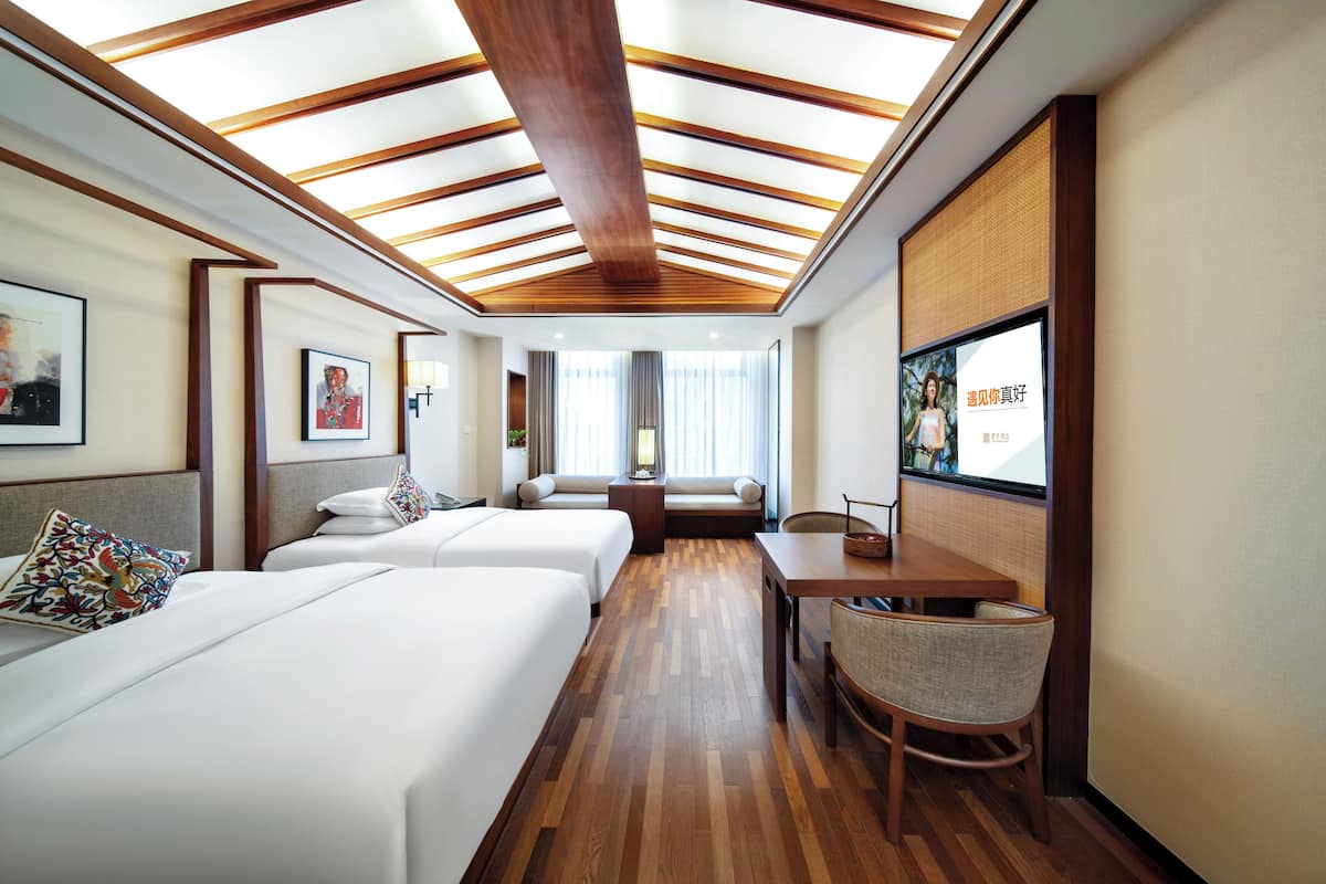 Une chambre d’hôtel avec deux lits, un plafond en bois, une télévision et un coin salon avec vue sur la pièce.