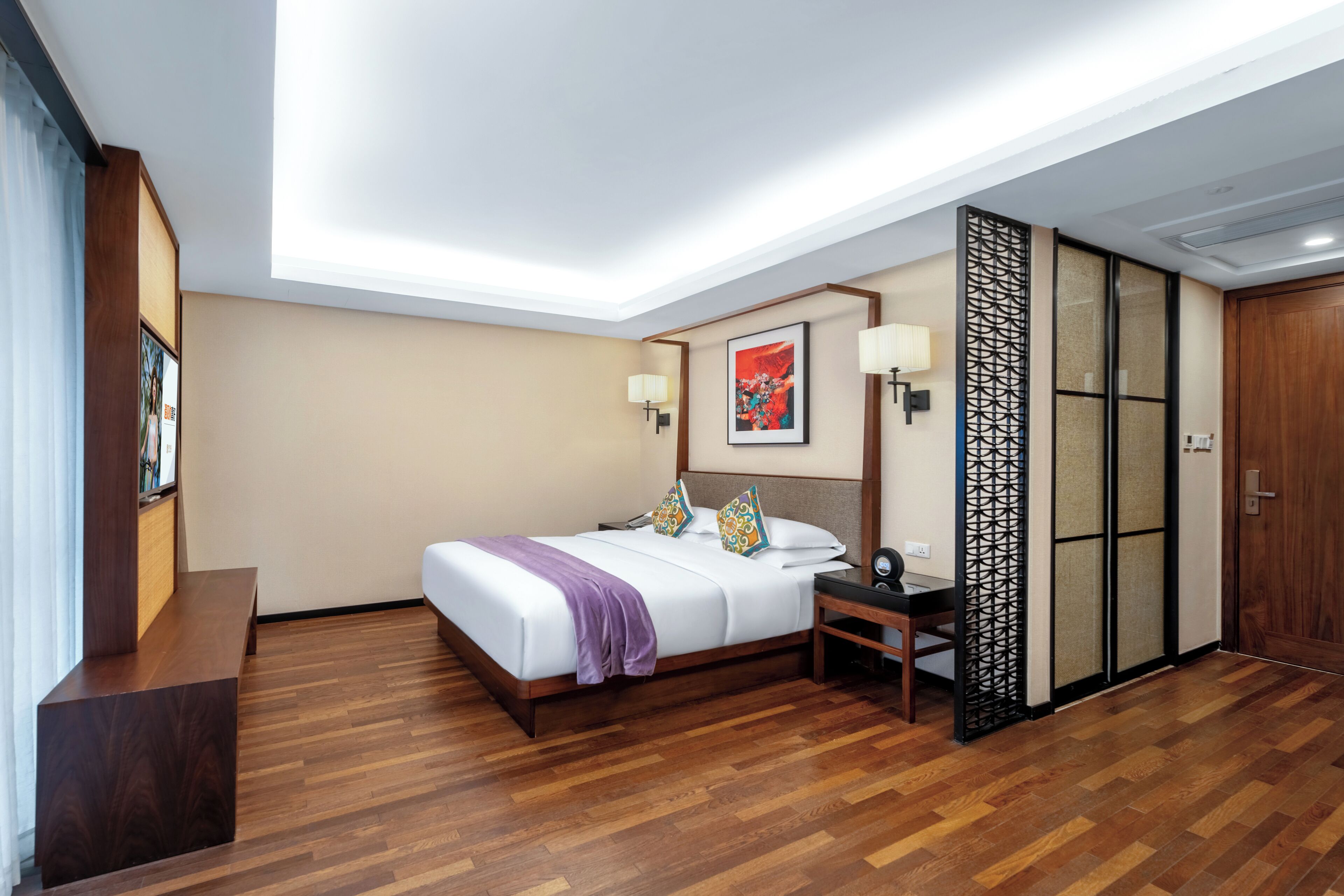 A hotel room with a large bed, bedside tables, a desk, and a sliding door.