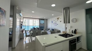 Une cuisine moderne dotée d’un îlot central, de meubles blancs et d’une hotte de cuisinière en acier inoxydable.