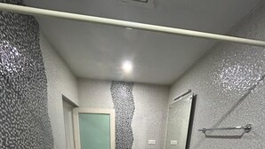 Une salle de bain avec des toilettes blanches, un lavabo avec un miroir et un espace douche.