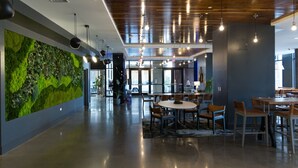 A modern interior with a green wall, wooden ceiling, and a dining area with tables and chairs. - Chique Loft 10 Min from NYC with Gym, Pool, Sauna (Jersey City)