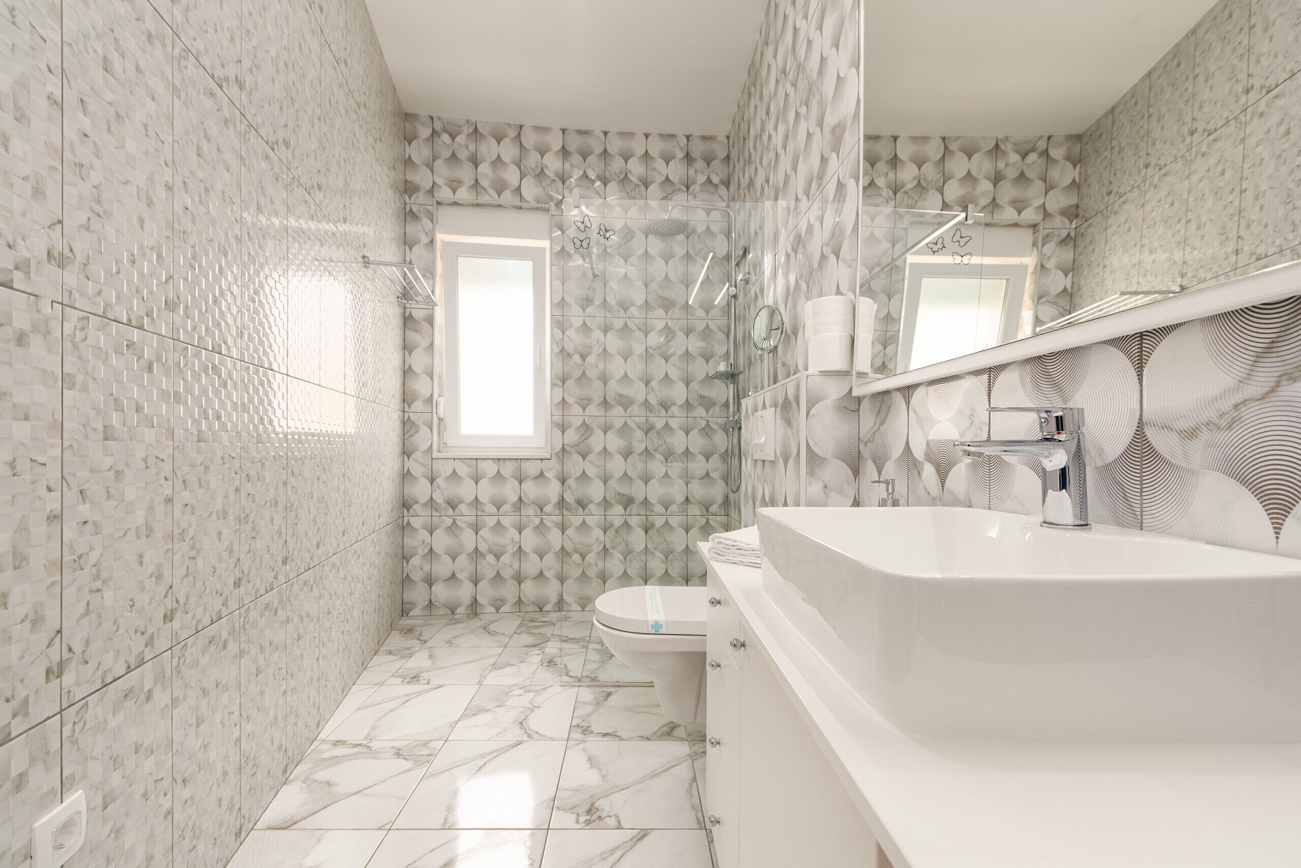 Un baño con diseño moderno, que cuenta con un lavamanos grande, un inodoro y una zona de ducha.