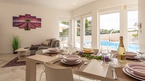 Un coin repas avec une table dressée pour quatre personnes, un canapé et un tableau accroché au mur.