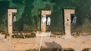 Vue aérienne d’une plage avec trois structures en béton, chacune ayant un bateau amarré à proximité.