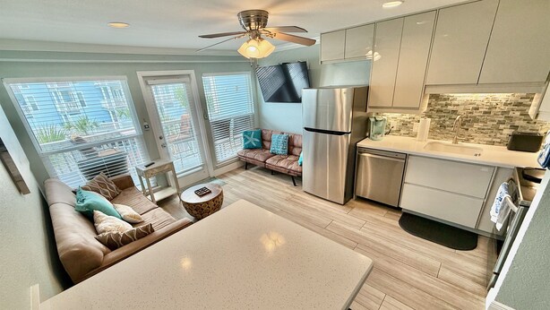 A modern kitchen with a central island, stainless steel appliances, and a ceiling fan. - Seascape 2202 The Seashell Pearl Beachfront Condo Gulf View Pool Hottubs Netflix (Galveston)