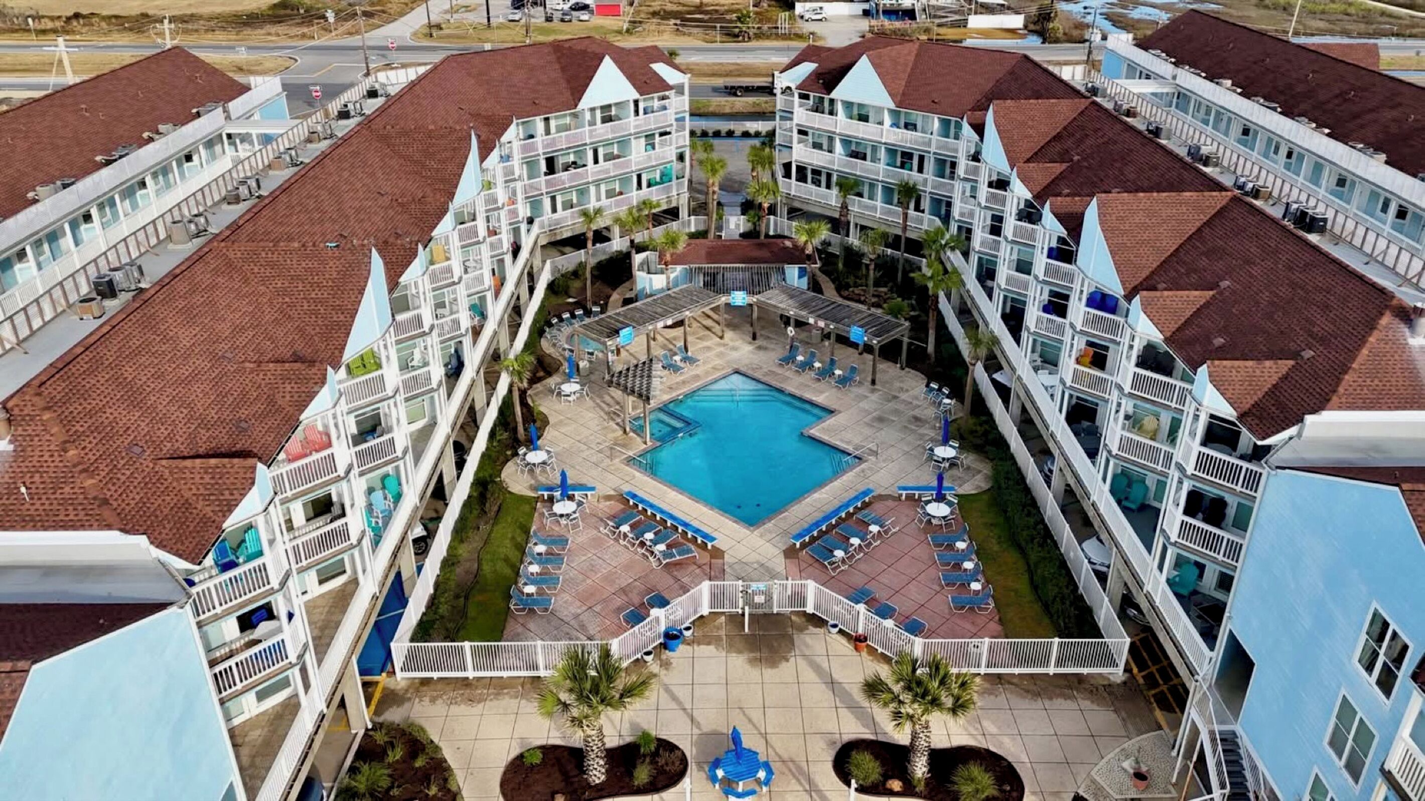 Un hotel con varios balcones, una piscina central y zonas de estar al aire libre.