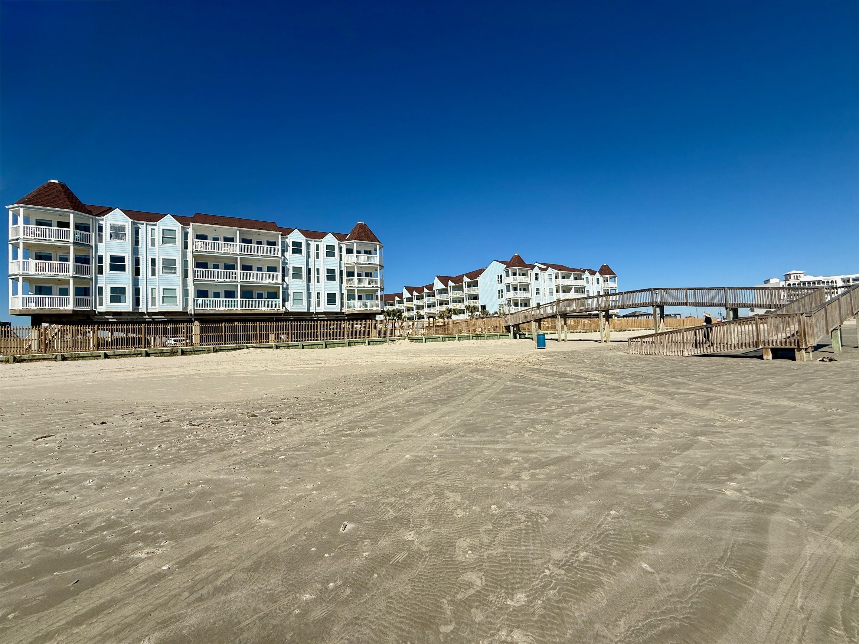 Un hôtel situé en bord de mer, doté de nombreux balcons et d’une promenade en bois.