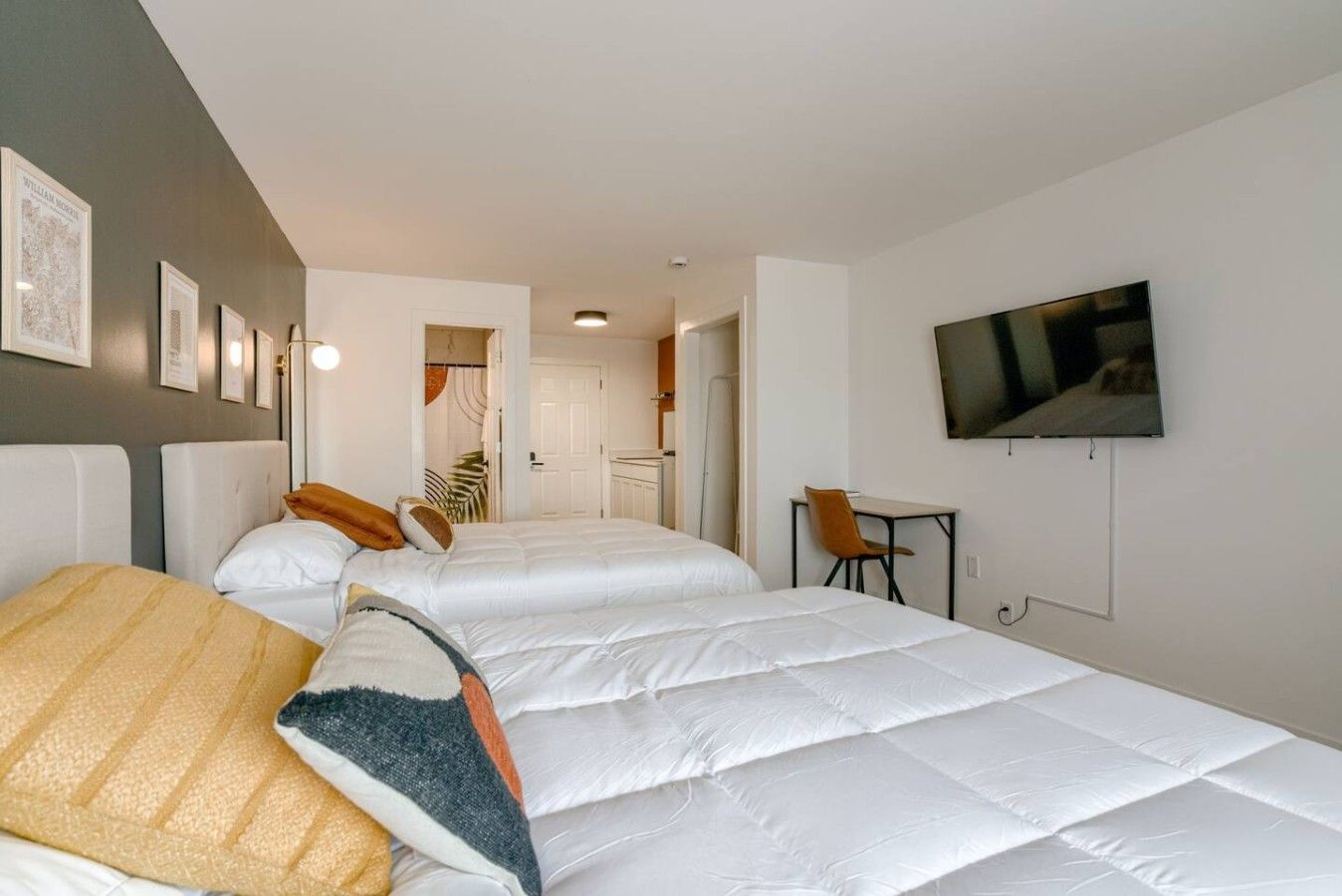 Habitación de hotel con dos camas, un televisor y un escritorio.