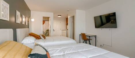 Habitación de hotel con dos camas, un televisor y un escritorio.