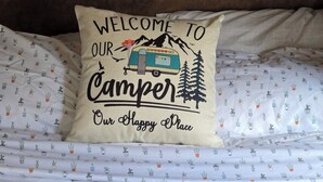 A bed with a pillow featuring a camper illustration and text. - Private space in a quiet area, great place to disconnect. (East Wenatchee)