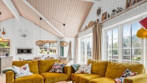 Una sala de estar acogedora con dos sofás color mostaza, una mesa de centro de madera y un ventanal con cortinas.
