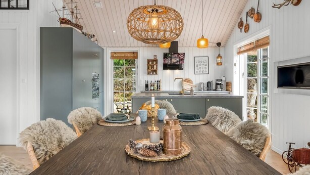 Un comedor con mesa de madera, sillas mullidas, un elegante accesorio decorativo en el centro y una lámpara colgante.