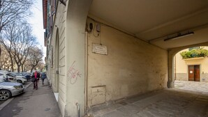 Un espace extérieur abrité, doté d’une enseigne fixée au mur, d’un coffret électrique et d’un sol pavé.