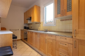 Een keuken met houten kastjes, een raam, een spoelbak en een fornuis.