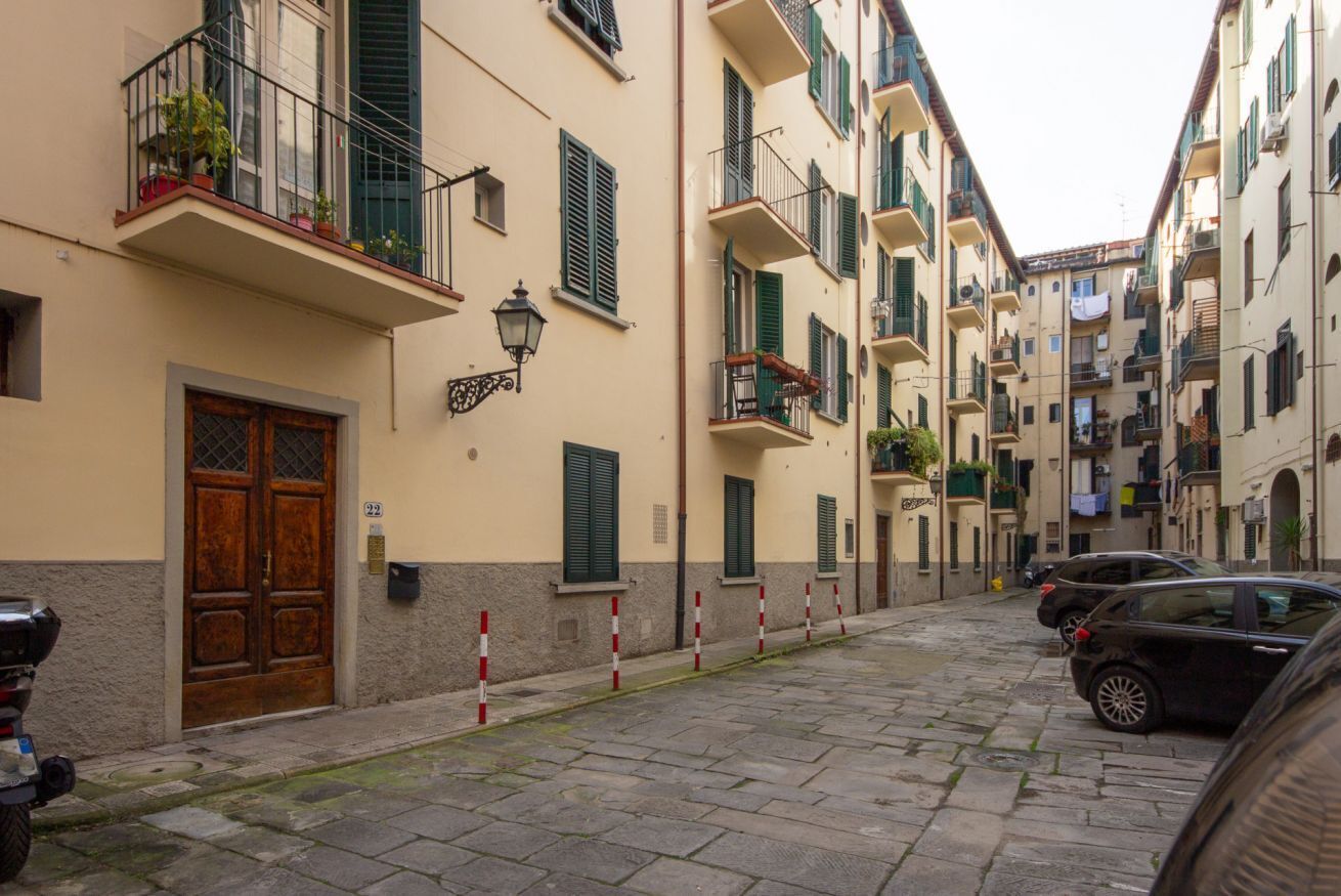 A narrow street with buildings, a wooden door, and a parked scooter.