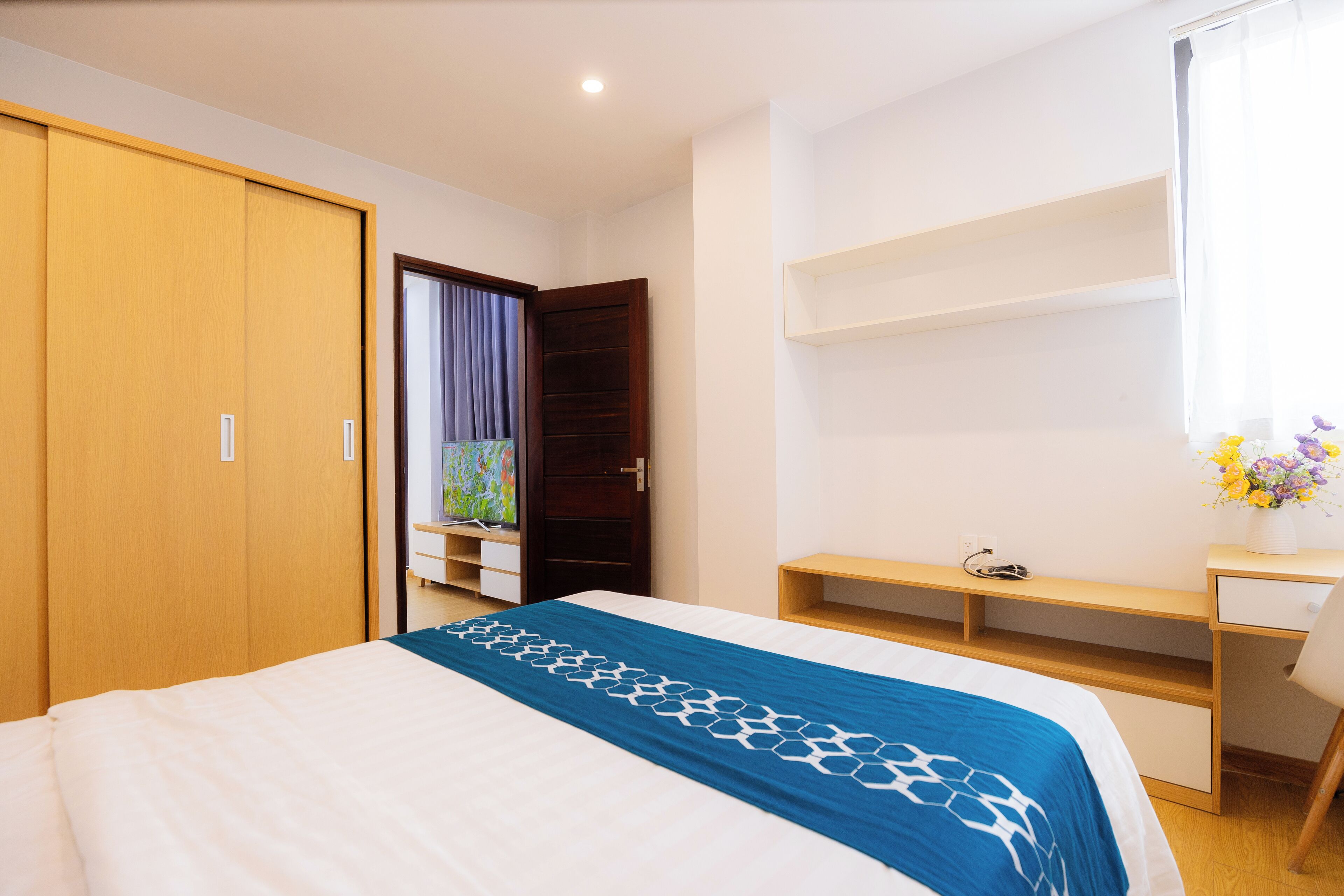 Ein Schlafzimmer mit einem Bett, einem Holzschrank, einem Schreibtisch und einem Fenster mit Vorhängen.