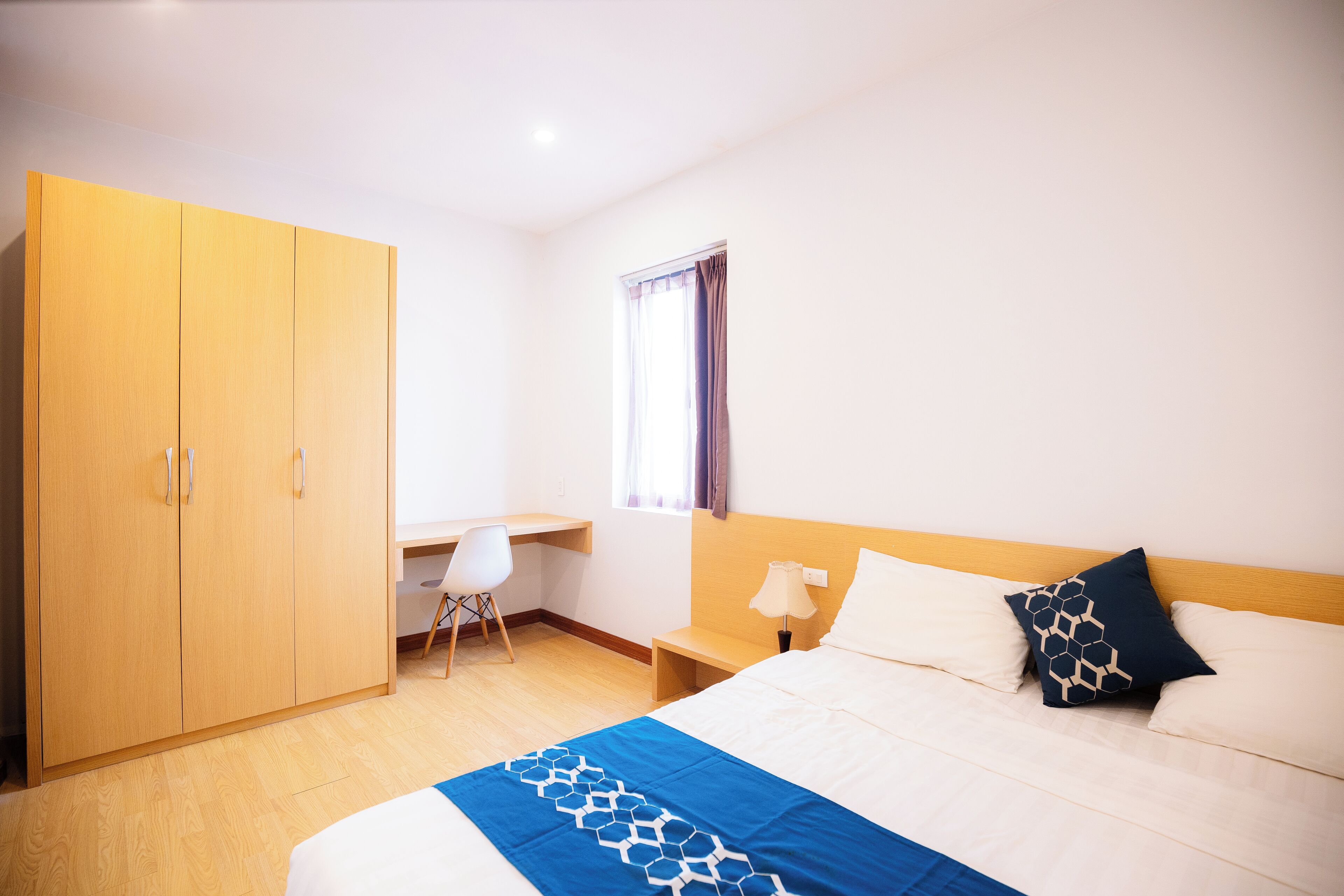 Una habitación de hotel con cama, escritorio, silla y armario.