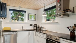 Una cocina moderna con gabinetes blancos, electrodomésticos de acero inoxidable y techo de madera.