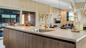 Une cuisine moderne dotée d’un grand îlot central, de meubles en bois et d’un évier en acier inoxydable.
