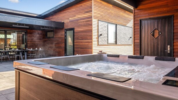 Un espace moderne aménagé à l’extérieur avec un jacuzzi, des panneaux de bois et une grande fenêtre.