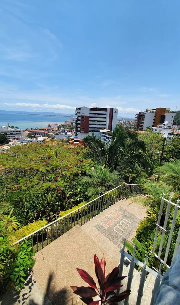 A coastal cityscape with modern buildings, a clear sky, and lush greenery. - Spacious hillside Villa with stunning bay&city views in Amapas, Puerto Vallarta (Puerto Vallarta)