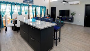 A modern kitchen with a granite countertop, black cabinetry, and a blue accent chair.