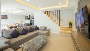A modern living room with a sofa, coffee table, and a staircase with integrated lighting.