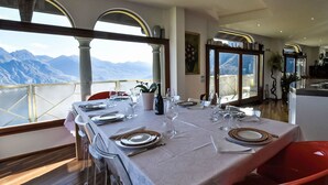 Un coin repas avec une table dressée pour quatre personnes, donnant sur un paysage montagneux.