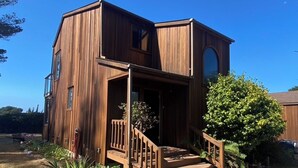 A two-story wooden house with a porch and a staircase. - Ocean View, Cozy 2-bedroom cabin in tranquil Gualala with WiFi and huge firepit (gualala)