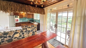 A kitchen with a stone island, wooden ceiling, and a view through glass doors. - Private house located 100 meters from the beach (Fare)