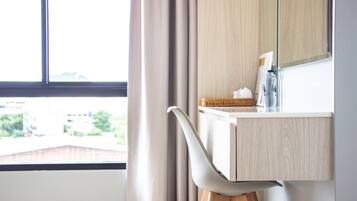 A modern bathroom with a wooden vanity, a mirror, and a window with curtains.