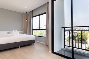 A modern bedroom with a large bed, a view of the city through large windows, and a balcony with a railing.
