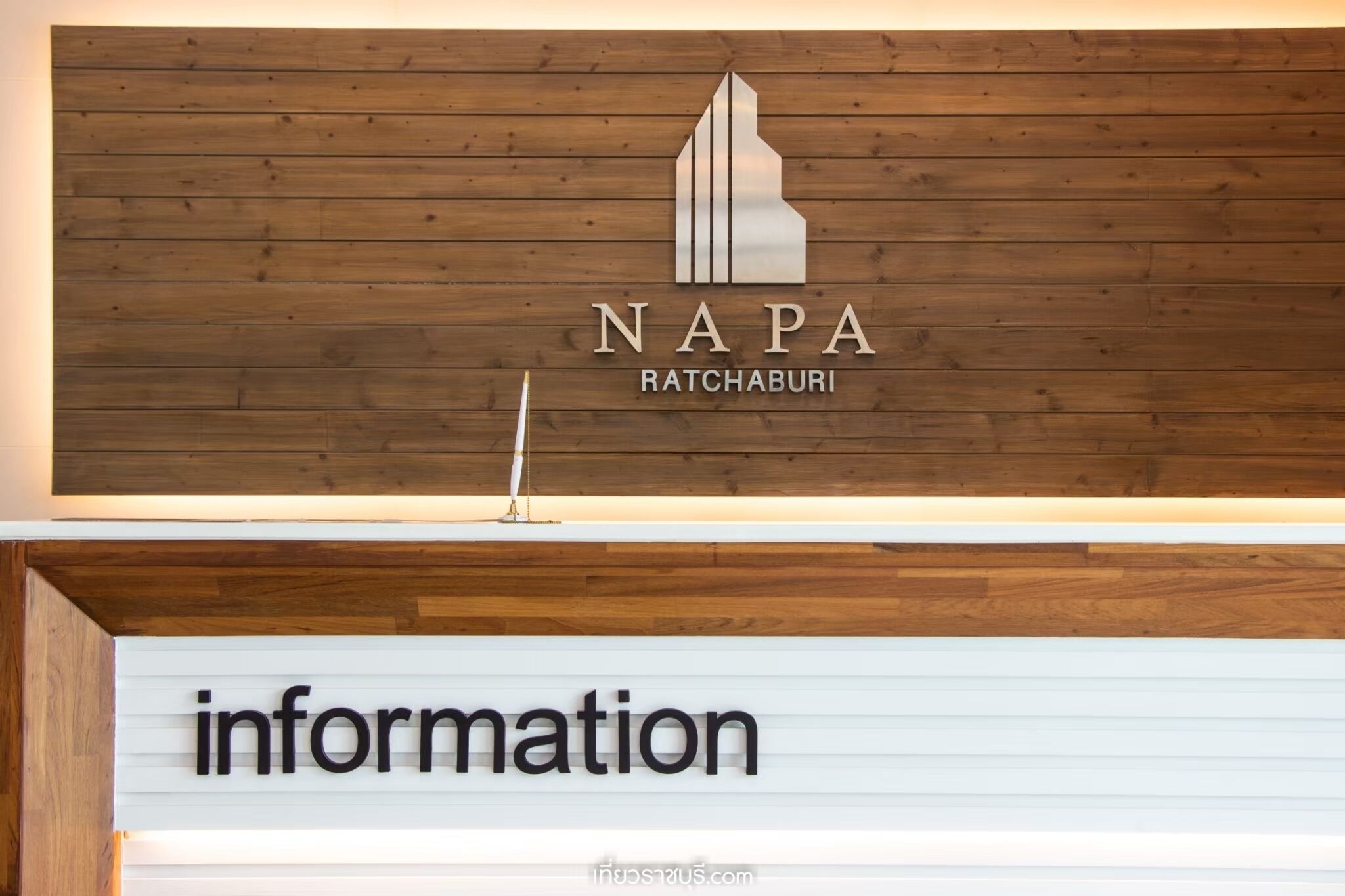 Eine Holzwand mit einem Logo und dem Text "NAPA RATCHABURI" über einem Schild mit der Aufschrift "information".