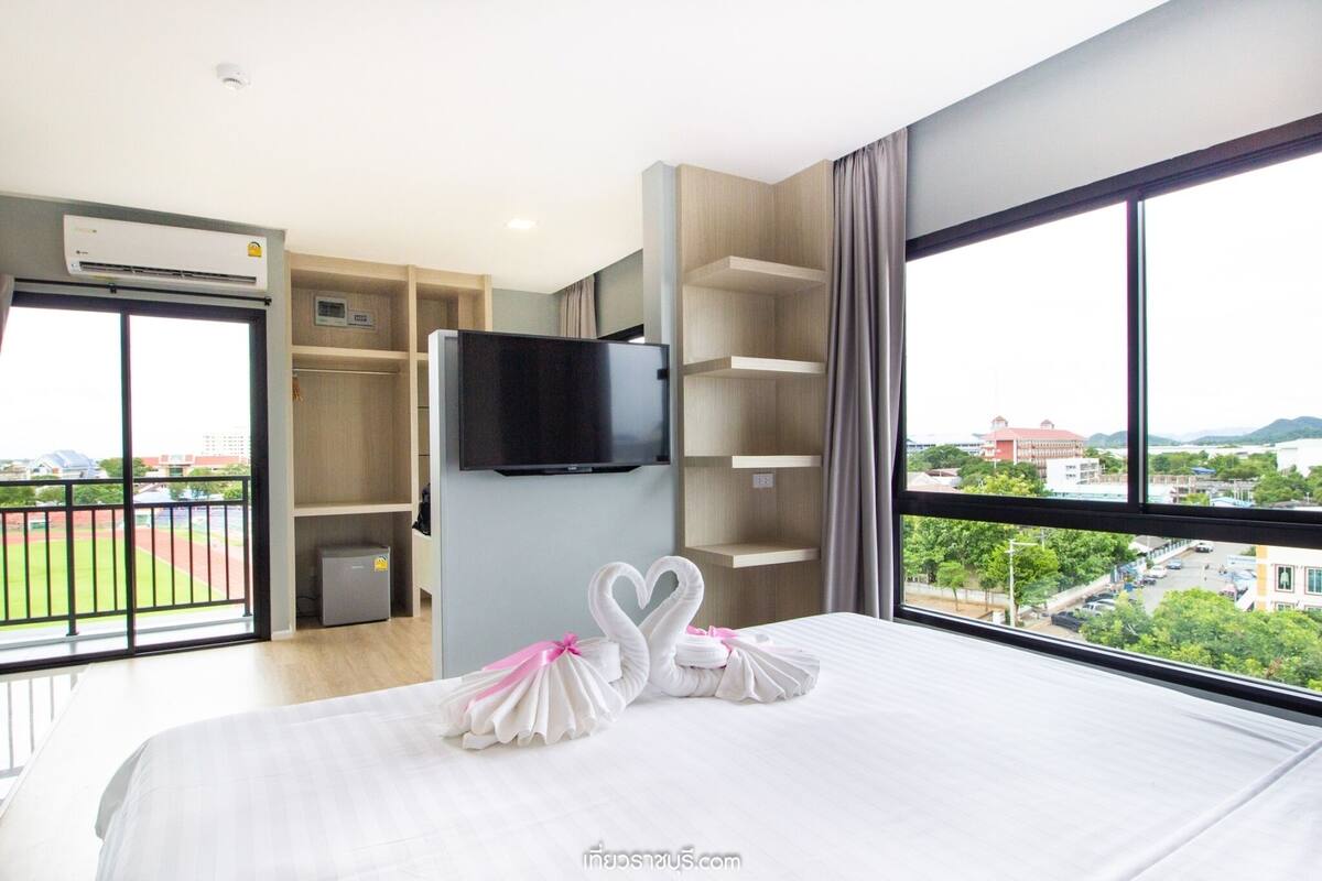 A hotel room with a bed, a TV, a balcony, and a view of the city.