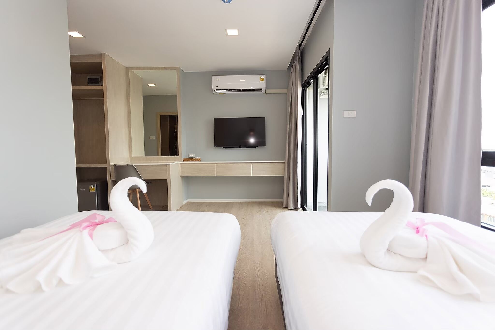 Una habitación de hotel con dos camas, televisión, aire acondicionado y un ventanal grande.