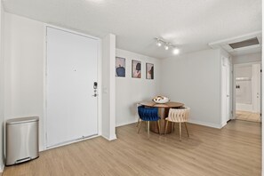 A modern, well-lit room with a wooden floor, a dining table with chairs, and a trash bin. - Oceanfront Oasis: Serene 1bd Retreat in MDR/Venice (Marina del Rey)