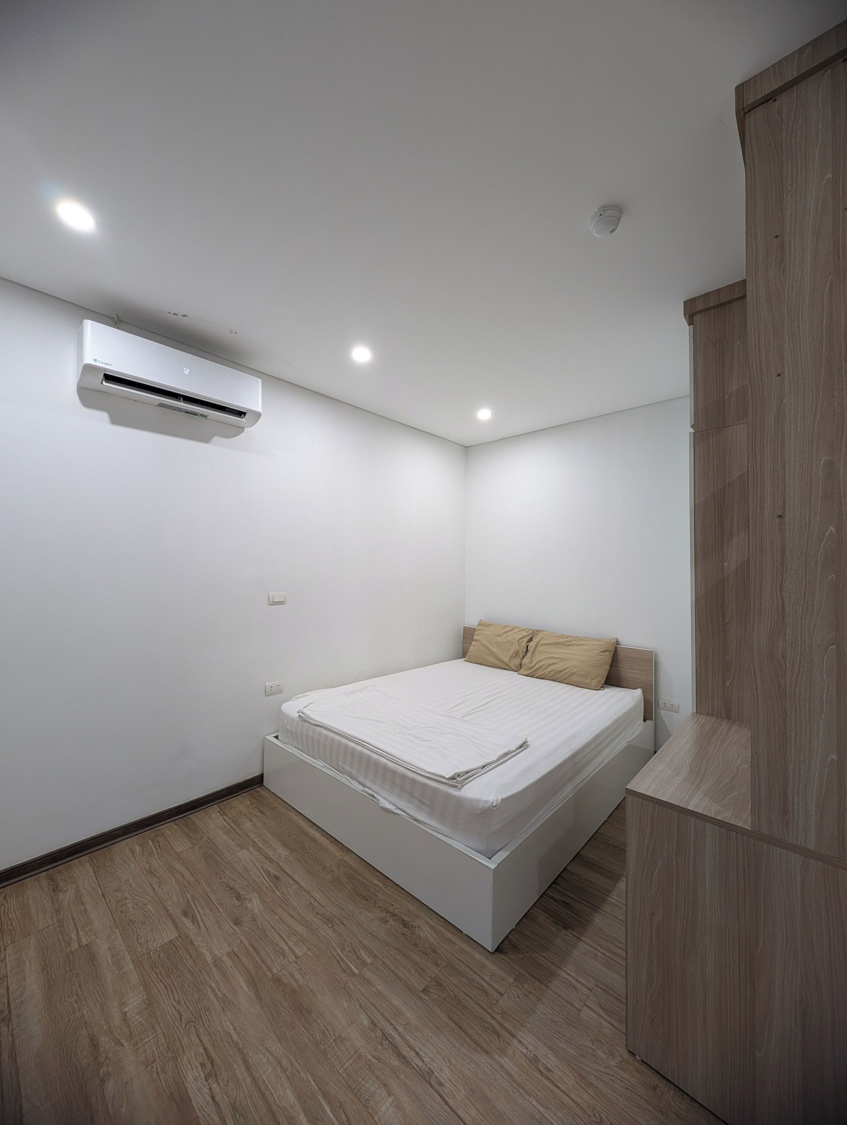 Una camera da letto moderna con un letto singolo, un condizionatore d'aria e un'armadio in legno.