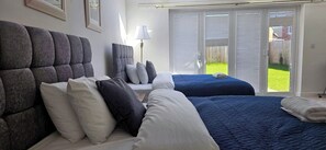 Een slaapkamer met twee bedden, een groot raam en uitzicht op een groen gazon.