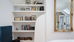Ein Zimmer mit einem weißen Bücherregal, einem großen Spiegel und einer blauen Heizung.