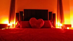A bed with a heart-shaped pillow and red bedding. -   Escape to Romance and Luxury (Hot Springs)