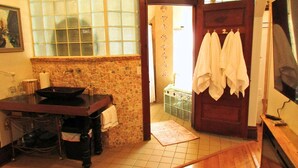 A bathroom with a stone wall, a sink, and a wooden door with towels hanging. -   Escape to Romance and Luxury (Hot Springs)