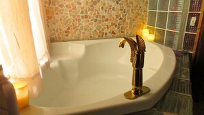 A bathtub with a gold faucet and mosaic tile walls. -   Escape to Romance and Luxury (Hot Springs)