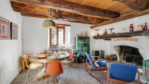 Un coin repas au style rustique, avec un plafond en bois, une table ronde et des chaises orange.