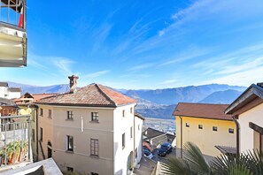 A building with a red-tiled roof, a balcony, and a view of mountains. - Lugano Bay View Twins, Cademario, Switzerland (Cademario)