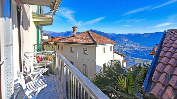A balcony with a view of mountains, a tiled roof, and a building with a balcony. - Lugano Bay View Due with Balcony for 4, Cademario, Switzerland (Cademario)