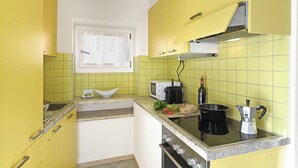 A kitchen with yellow cabinets, a microwave, a stove, and a coffee maker. - Lugano Bay View Due with Balcony for 4, Cademario, Switzerland (Cademario)